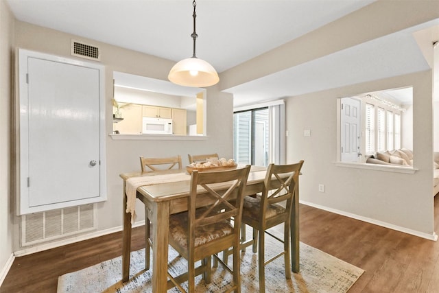dining space with visible vents, baseboards, and wood finished floors