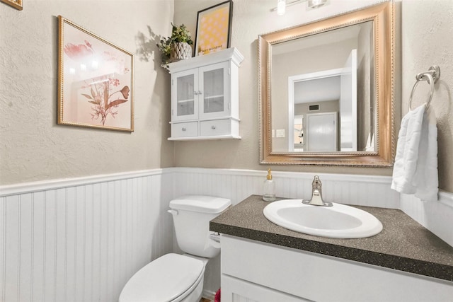 half bath featuring vanity, toilet, and visible vents