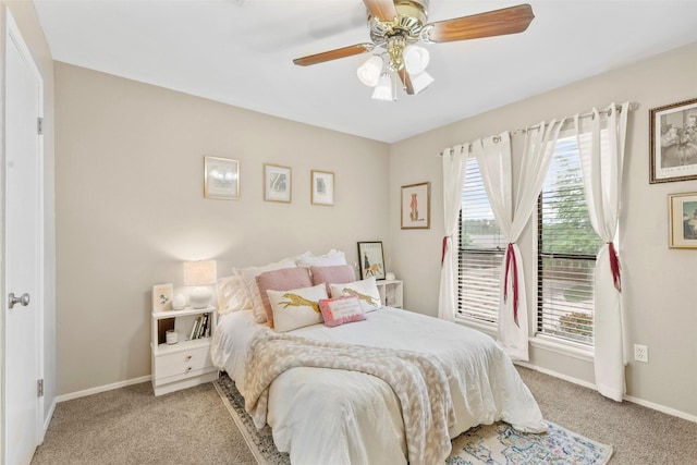 carpeted bedroom with a ceiling fan, baseboards, and multiple windows