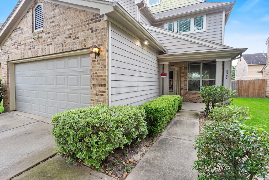 view of front of property with concrete driveway, brick siding, fence, and a garage