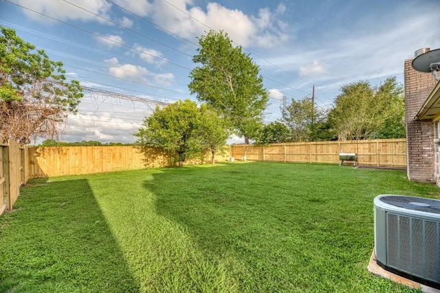 view of yard with a fenced backyard and central AC