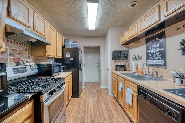 kitchen with a textured ceiling, a sink, black appliances, light wood finished floors, and under cabinet range hood
