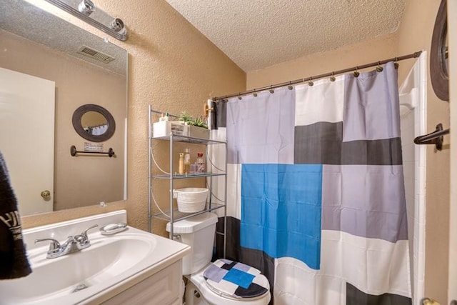 bathroom featuring a textured ceiling, visible vents, vanity, toilet, and a textured wall