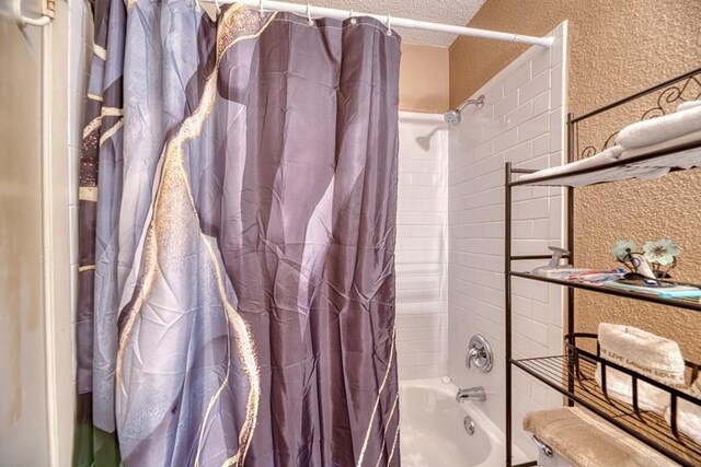 full bathroom featuring shower / bath combo with shower curtain and a textured ceiling