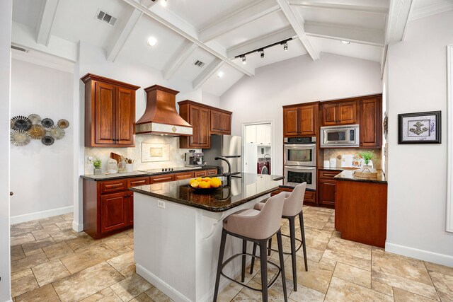 kitchen with premium range hood, baseboards, stainless steel appliances, and stone tile flooring