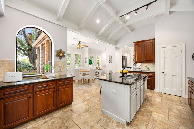 kitchen with stone tile flooring, vaulted ceiling with beams, tasteful backsplash, a sink, and dishwasher
