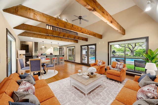 living area with light wood-style floors, ceiling fan, beam ceiling, and high vaulted ceiling
