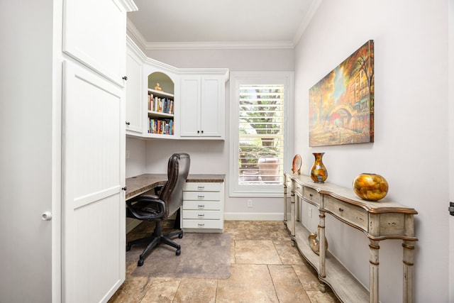 home office featuring crown molding, baseboards, stone finish floor, and built in desk