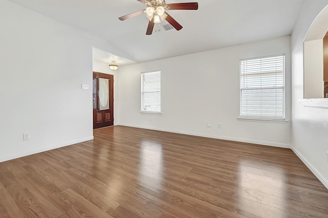 unfurnished room featuring vaulted ceiling, a ceiling fan, wood finished floors, baseboards, and arched walkways