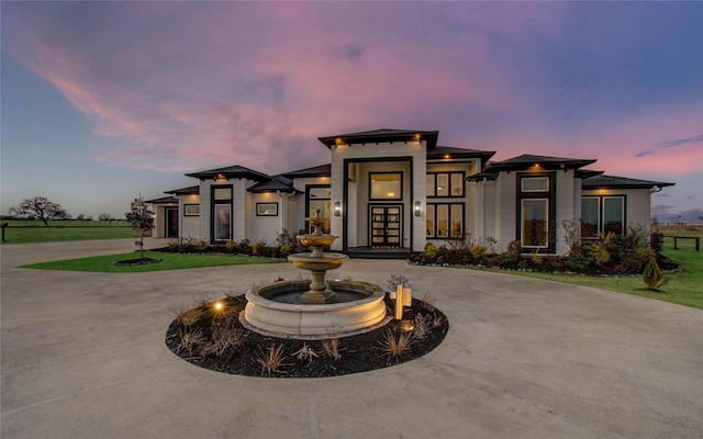 prairie-style house with curved driveway, french doors, and a front yard