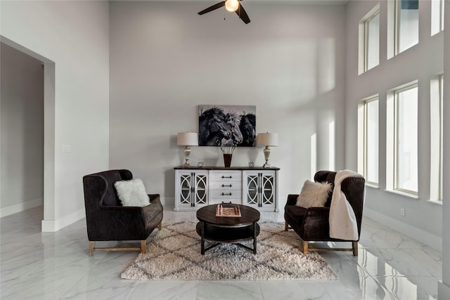 sitting room featuring baseboards, a high ceiling, a ceiling fan, and marble finish floor