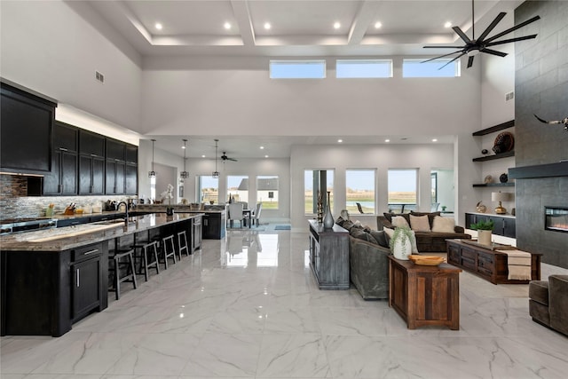 living area with a ceiling fan, a high ceiling, visible vents, and marble finish floor