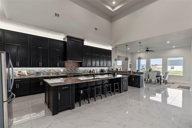 kitchen featuring dark cabinetry, a breakfast bar area, visible vents, and stainless steel fridge with ice dispenser