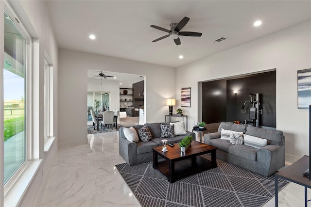 living room featuring a ceiling fan, visible vents, plenty of natural light, and marble finish floor