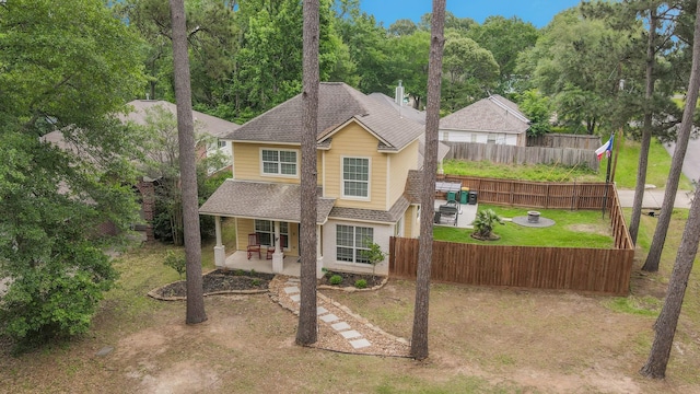 traditional-style home featuring fence, a patio, and a shingled roof
