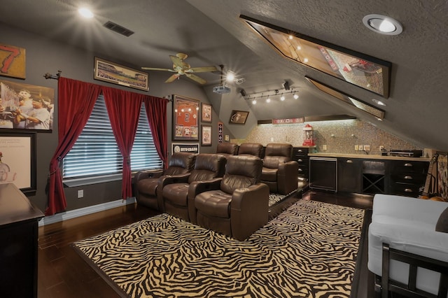 home theater featuring ceiling fan, a textured ceiling, wood finished floors, lofted ceiling, and visible vents