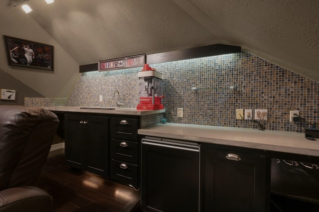 bar featuring backsplash, dark wood-style flooring, a textured ceiling, and vaulted ceiling