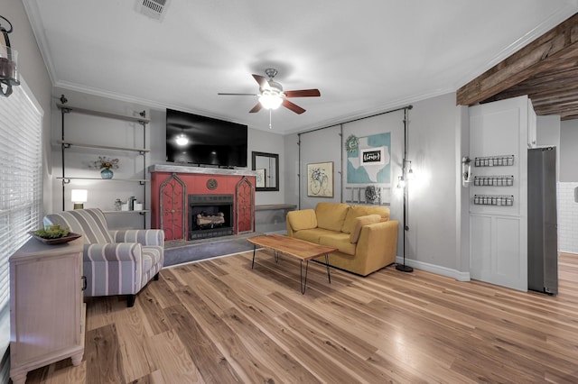 living room featuring crown molding, ceiling fan, visible vents, and light wood-type flooring