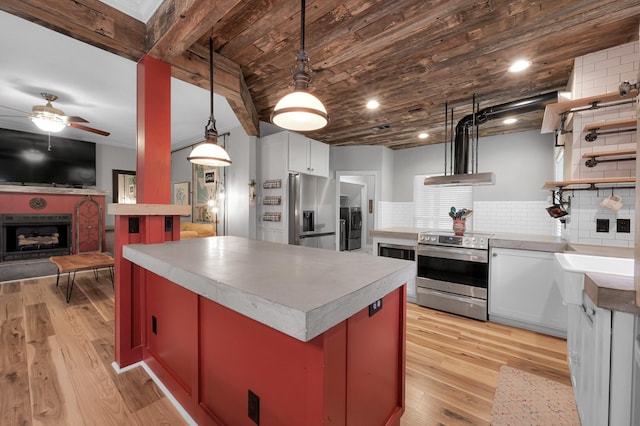 kitchen with decorative backsplash, a fireplace, light countertops, a ceiling fan, and stainless steel appliances