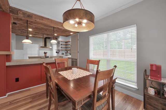 dining space featuring baseboards, an inviting chandelier, ornamental molding, and light wood finished floors