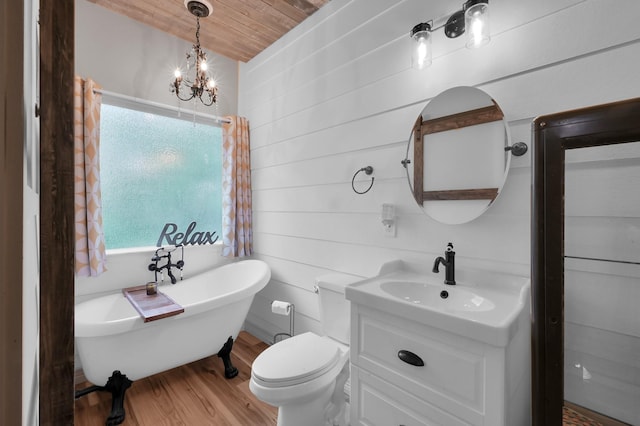 bathroom with wood finished floors, a healthy amount of sunlight, a soaking tub, and vanity
