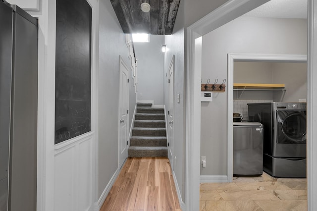 interior space with light wood-type flooring, stairs, and washing machine and dryer