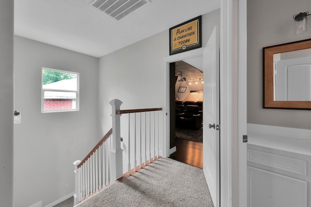hall with baseboards, carpet, an upstairs landing, and visible vents