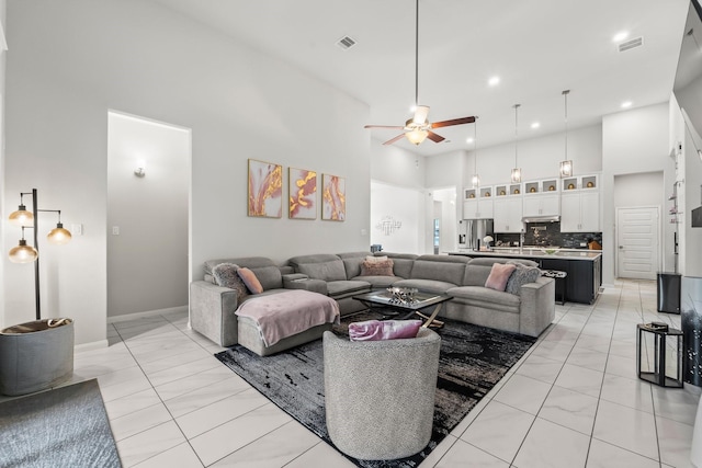 living room featuring ceiling fan, recessed lighting, visible vents, and a towering ceiling