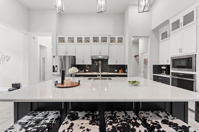kitchen with decorative light fixtures, appliances with stainless steel finishes, tasteful backsplash, a breakfast bar, and under cabinet range hood