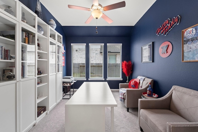 carpeted office featuring a ceiling fan, a textured wall, and vaulted ceiling