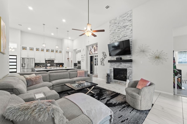 living area with ceiling fan, a fireplace, marble finish floor, a towering ceiling, and visible vents