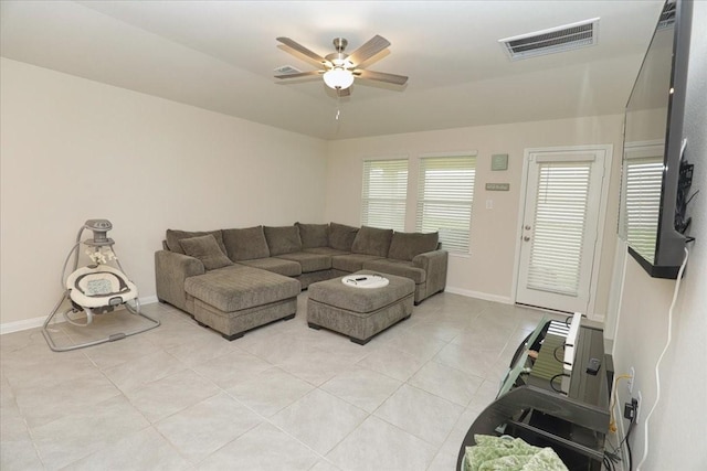 living area featuring light tile patterned floors, baseboards, ceiling fan, and visible vents