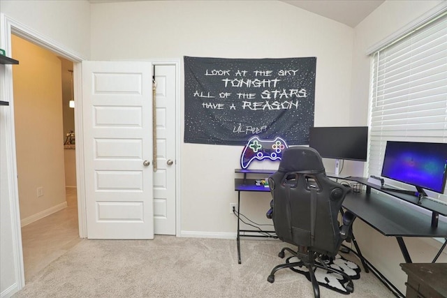 carpeted office space featuring baseboards and vaulted ceiling