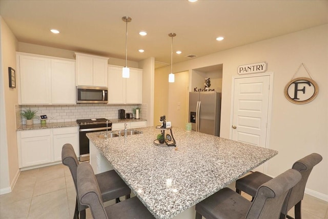 kitchen with a kitchen breakfast bar, tasteful backsplash, a sink, stainless steel appliances, and light tile patterned flooring