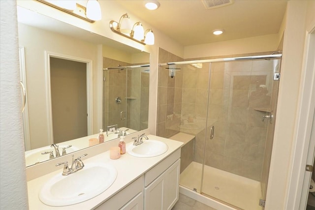 full bath featuring visible vents, a sink, double vanity, and a shower stall