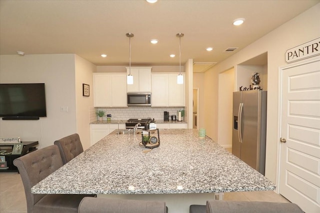 kitchen with light stone counters, appliances with stainless steel finishes, a breakfast bar area, and tasteful backsplash