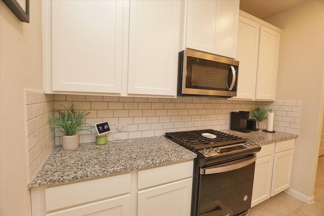 kitchen featuring backsplash, stainless steel microwave, gas range oven, and light stone counters