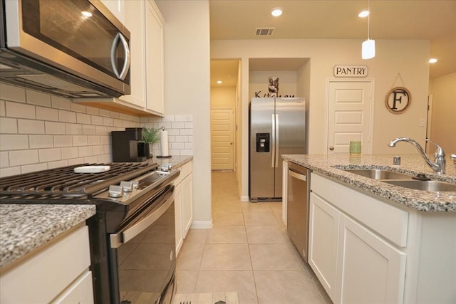 kitchen featuring backsplash, decorative light fixtures, a sink, stainless steel appliances, and white cabinetry