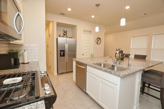 kitchen featuring visible vents, decorative backsplash, a sink, light tile patterned floors, and stainless steel appliances