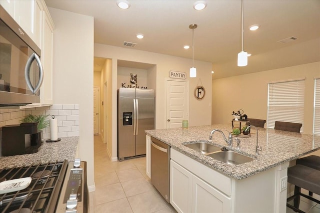 kitchen featuring white cabinets, light tile patterned flooring, appliances with stainless steel finishes, a sink, and visible vents