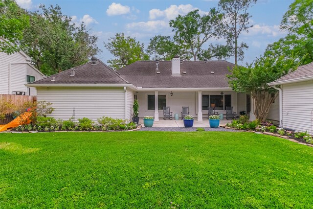 rear view of property featuring a yard, fence, a chimney, and a patio area