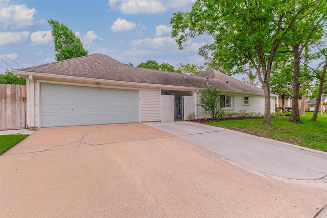 single story home featuring an attached garage, a front lawn, fence, and concrete driveway