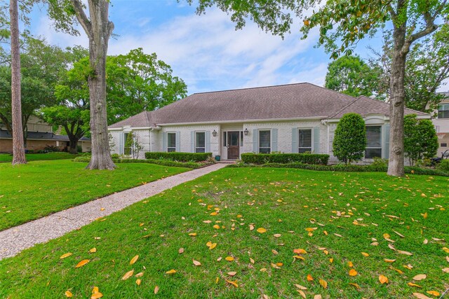 ranch-style house with roof with shingles, a front lawn, and brick siding
