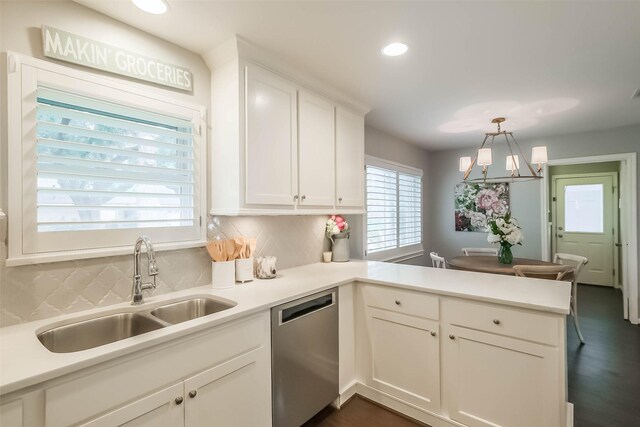 kitchen featuring white cabinets, a sink, dishwasher, a peninsula, and decorative backsplash