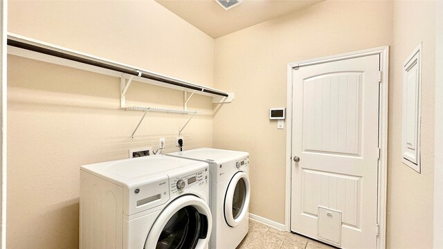 laundry area with laundry area, visible vents, washing machine and clothes dryer, baseboards, and light tile patterned flooring