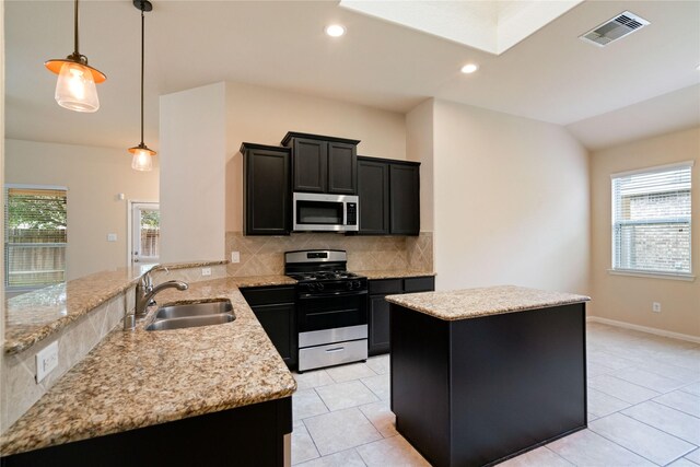 kitchen featuring appliances with stainless steel finishes, a sink, a peninsula, a kitchen island, and visible vents