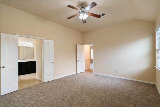 unfurnished bedroom with baseboards, visible vents, vaulted ceiling, and light colored carpet
