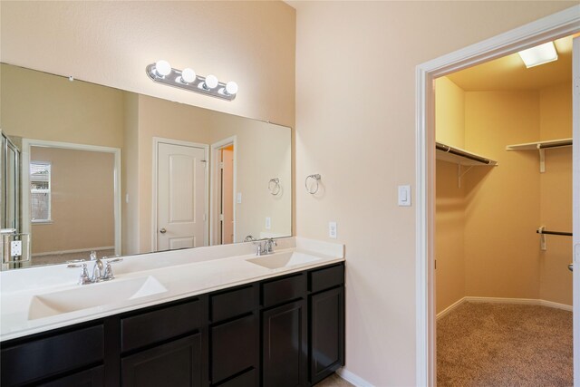 full bath with a sink, baseboards, double vanity, and a spacious closet