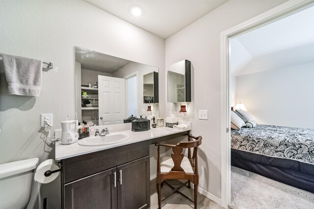 ensuite bathroom with vanity, baseboards, toilet, and ensuite bath