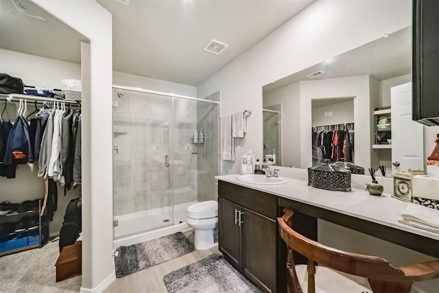 full bathroom featuring vanity, toilet, a walk in closet, and a stall shower